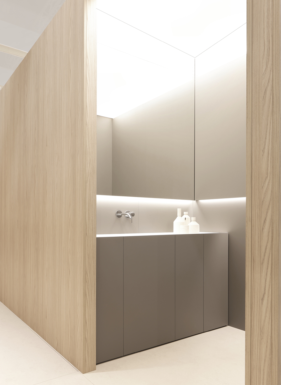 Minimalist bathroom with sleek gray cabinetry and light wood walls.