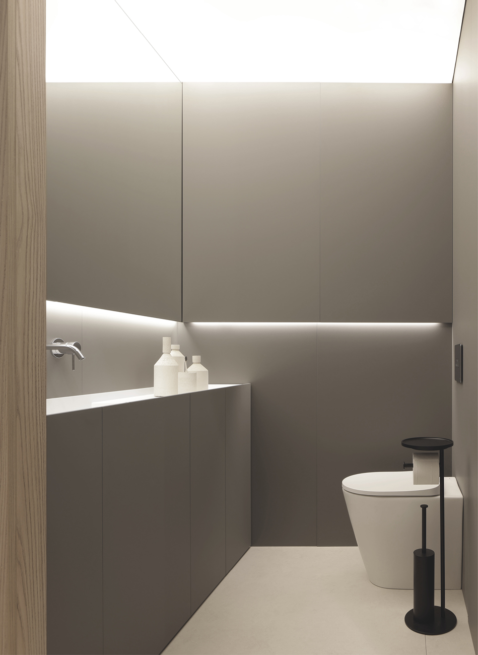 Bagno minimalista con sanitari moderni e illuminazione soffusa.