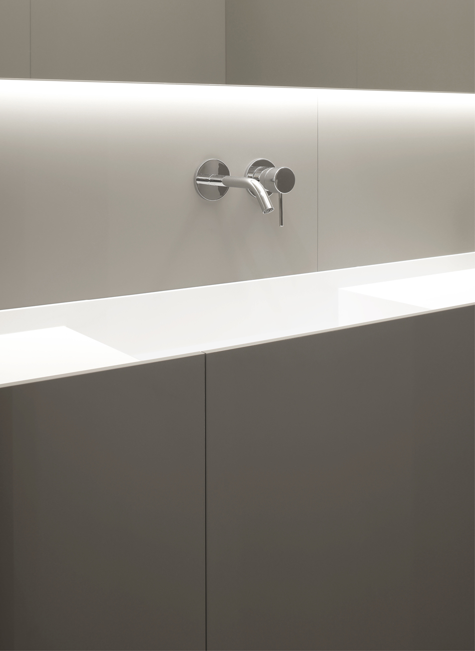 Rubinetto in acciaio inox su parete bianca in bagno minimalista.