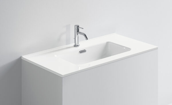 Lavabo bianco con rubinetto in acciaio inox in bagno minimalista.