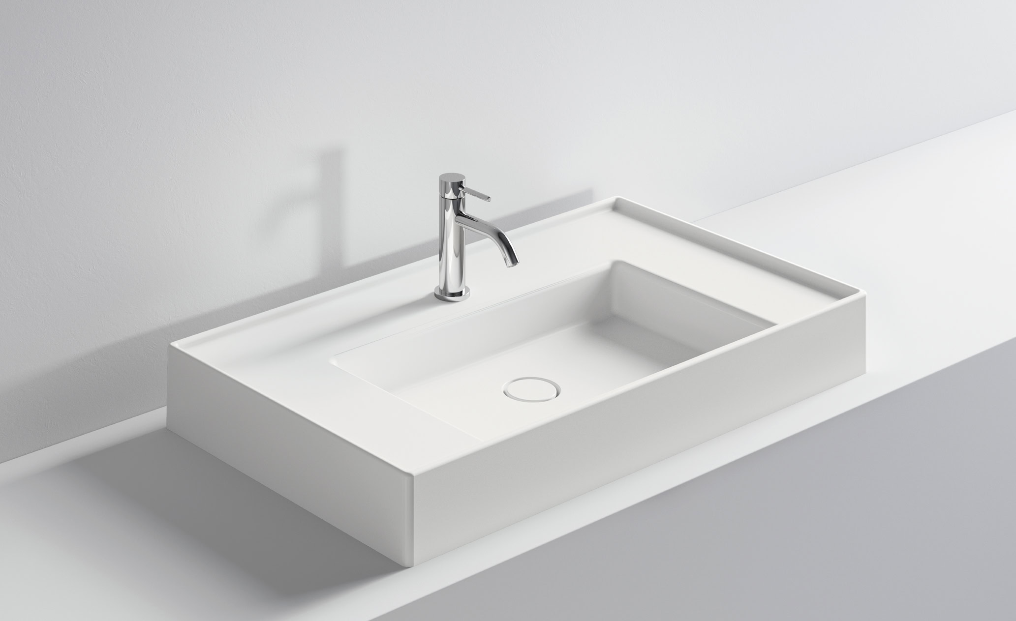 Lavabo bianco con rubinetto in acciaio inox su superficie bianca.