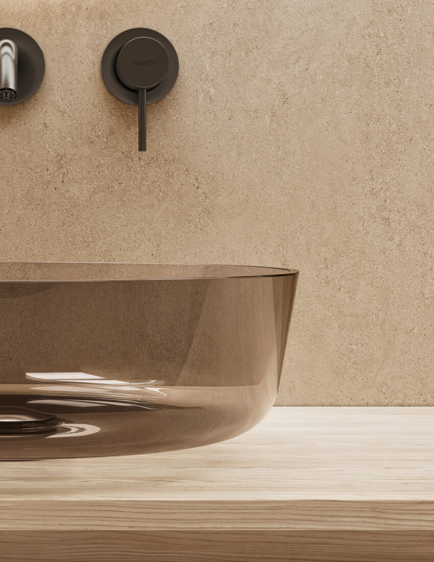 Vasca da bagno in vetro color marrone con rubinetto nero e parete beige.