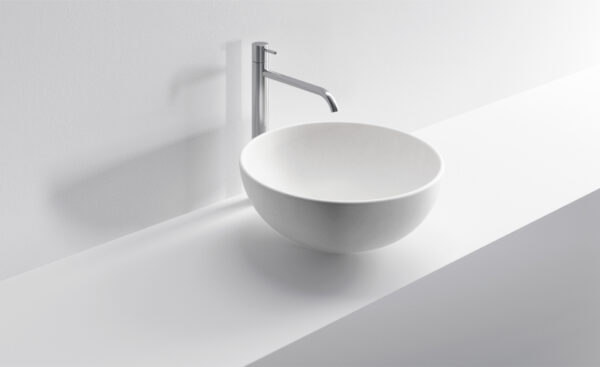 Lavabo rotondo in ceramica bianca con rubinetto moderno.