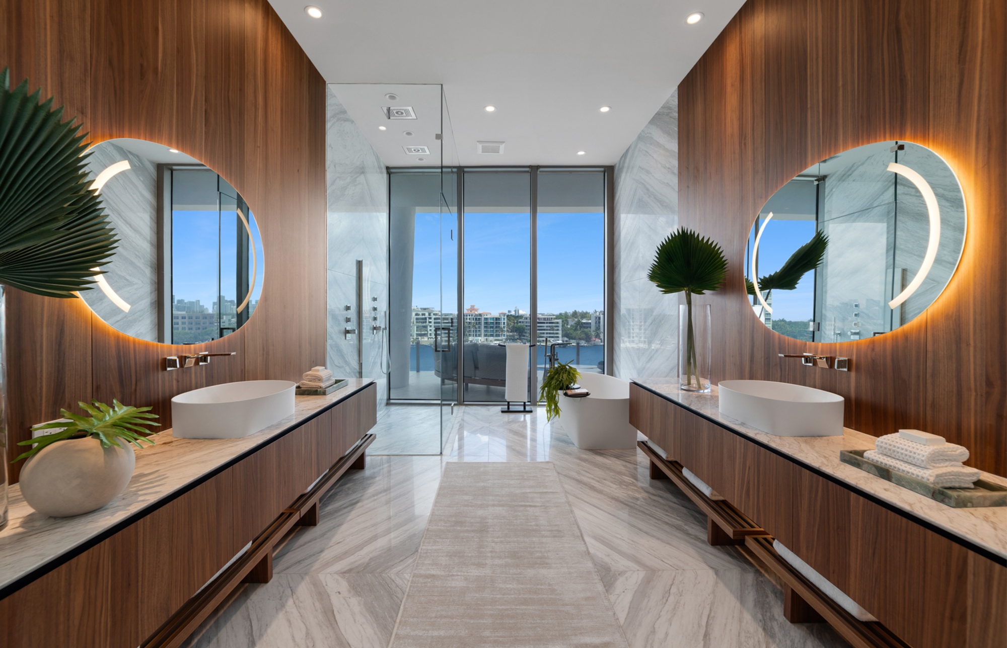 Bagno moderno con specchi rotondi illuminati e viste urbane.