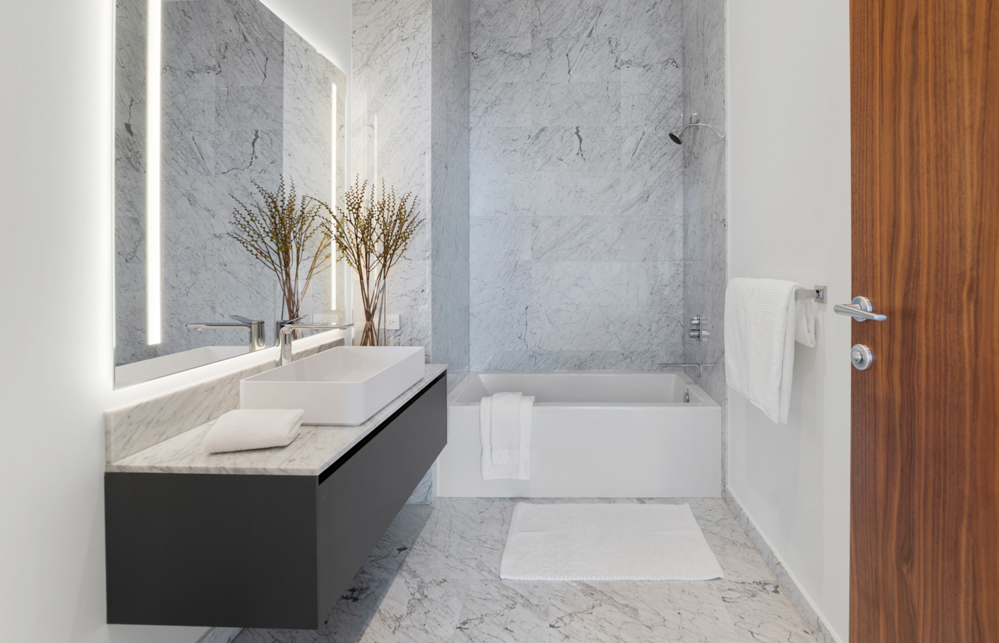 Bagno elegante in marmo grigio con lavabo sospeso e vasca.